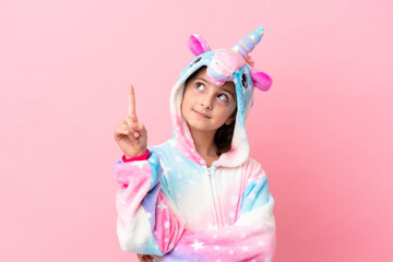 Little caucasian woman wearing a unicorn pajama isolated on pink background pointing up a great idea