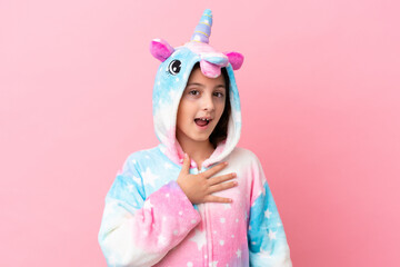 Little caucasian woman wearing a unicorn pajama isolated on pink background surprised and shocked while looking right