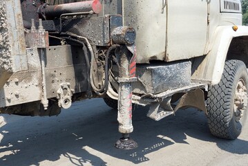 part of a gray dirty truck with a crane with an iron hydraulic stop on the street on the road