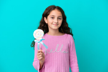 Little caucasian girl holding a lollipop isolated on blue background smiling a lot