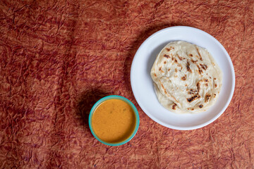 Parotta with chicken curry on a white plate. is a delicacy from the state of Kerala