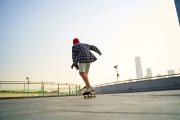 Rolgordijnen teenage asian boy skateboarding outdoors © imtmphoto