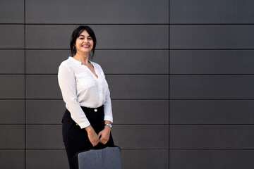 smiling businesswoman holding a briefcase - obrazy, fototapety, plakaty