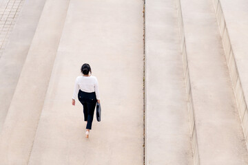 woman walking with a briefcase on a concrete floor