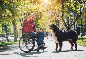 Happy young man with a physical disability who uses wheelchair with his dog.