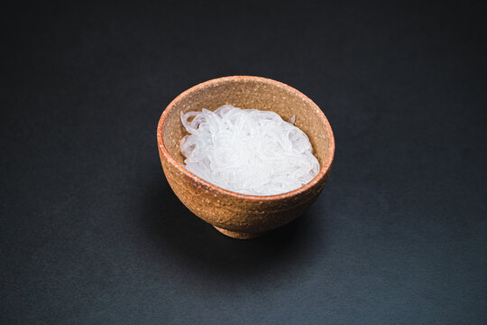 Japanese Shirataki noodles in traditional clay bowl. Black background. 