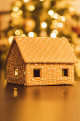 Classic Scandinavian Christmas gingerbread house in front of Christmas tree with bokeh - Portrait Tight 