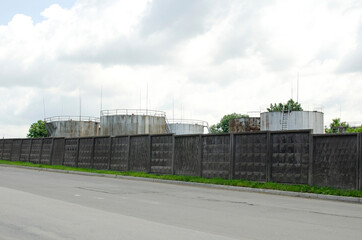 Fototapeta na wymiar Oil storage tanks behind the concrete fence