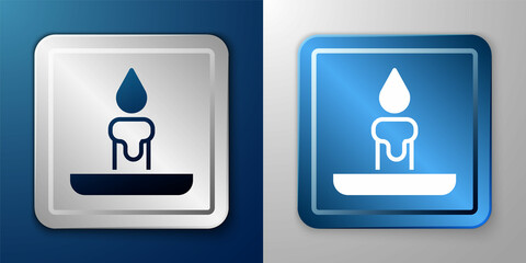 White Burning candle in candlestick icon isolated on blue and grey background. Cylindrical candle stick with burning flame. Silver and blue square button. Vector