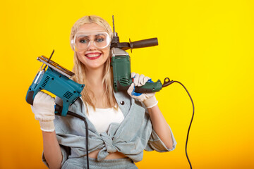 Beautiful girl with an electric drill and an electric jigsaw.