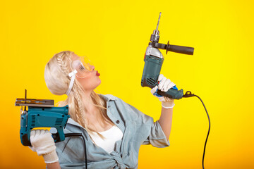 Beautiful girl with an electric drill and an electric jigsaw.