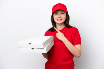 Young Russian pizza delivery picking up pizza boxes isolated on white background pointing to the...