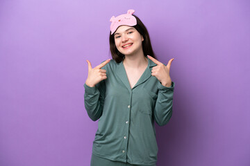 Obraz na płótnie Canvas Young Russian woman in pajamas isolated on purple background giving a thumbs up gesture