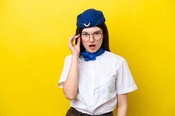 Airplane stewardess Russian woman isolated on yellow background with glasses and surprised