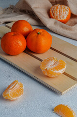 Orange ripe tangerines on a light plaque close-up, slices of peeled tangerine. Bright tangerines on a light background.