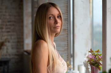 Fototapeta premium portrait of a beautiful blonde girl near the window.looks at the camera.