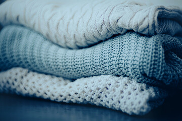 Fototapeta na wymiar Three warm woolen knitted sweaters are stacked in a pile. Beautiful casual clothes for everyday wear in cold weather. Wardrobe.