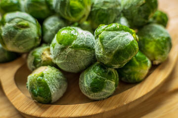 frozen frosty brussels sprouts on wooden plate closeup