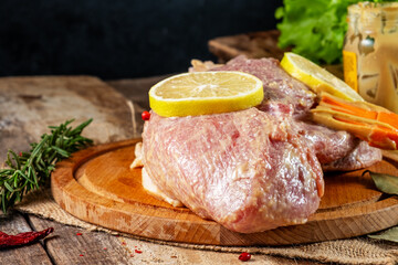 Pork marinated in mustard and lemon lies on a wooden table.