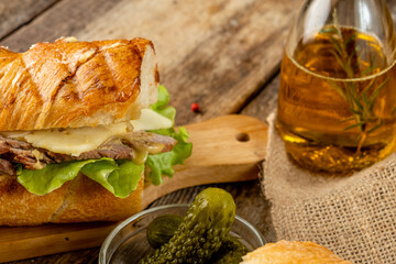 Sandwich with meat, vegetables and cheese on a wooden table. Close-up. Selective focus.