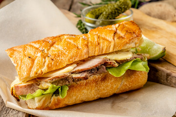 Sandwich with meat, mustard sauce and cheese on a wooden background.