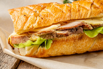 Cuban sandwich with baked meat and vegetables in a crispy bun in butter. Close-up.
