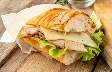 Cubano sandwich with baked meat and vegetables in a crispy bun in butter. Close-up. Selective focus