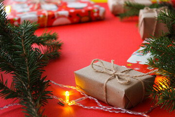 Christmas composition with gift boxes, clews of rope, paper's rools and decorations, fir tree branches on red background. Preparation for holidays. Top view with copy space, flat lay, layout, flatly.