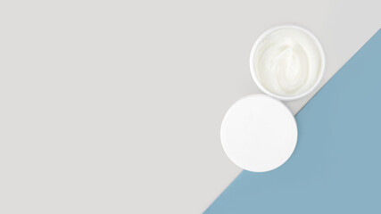 An open jar with white natural, Hypoallergenic eco cream for the face or body on a minimalistic blue background. Skincare concept. Horizontal. Banner. Copy space. Top view.