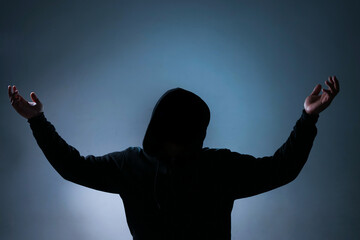 a silhouette of an unidentified person. a person wearing a black hoodie represents an anonymous...