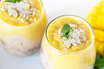 Delicious mango and chia pudding in a glass on the white ceramic tile table close up. Healthy morning breakfast concept