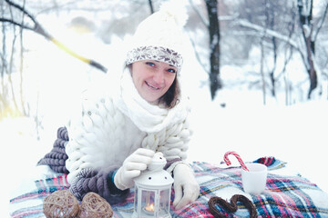 The girl lies on the snow in the winter forest or park. Concept - Christmas vacations and holidays.