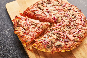 Fast food, Baked frozen pizza with ham, mushrooms and cheese on thick dough. Ready to eat.