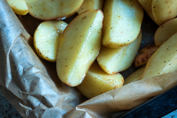 fresh raw potatoes wedges mixed with oil and spices ready for baking closeup