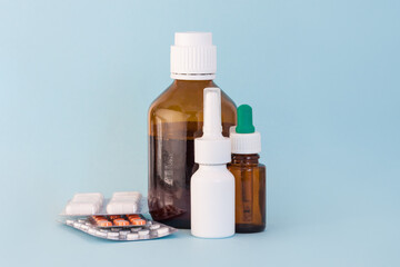 Set of medicine, nasal spray, syrup, drops, vitamines on blue background.