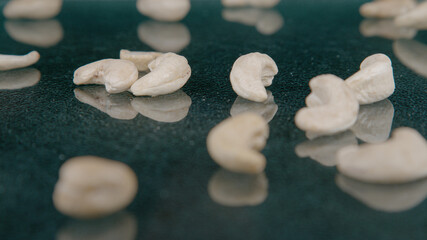 MACRO: A handful of cashews falls onto the polished surface of a dining table.