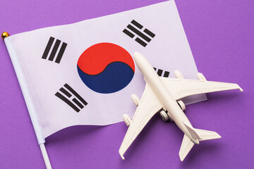 Flag of South Korea and a toy plane on a colored background, the concept on the theme of travel to the country © Sergey Chayko
