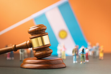 Judge gavel against the background of a blurred flag and plastic toy men, the concept of a trial in Argentine society