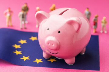 Piggy bank, EU flag and plastic toy men on a colored background, a concept on the theme of the income of the population of the European Union