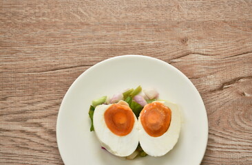 boiled spicy salty egg half cut with slice shallot and chili salad on plate