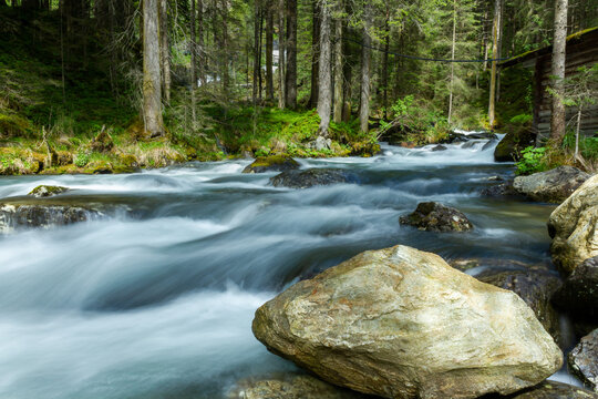 The 'Riesachbach' mountain creek flowing downhill through forest landscape with long exposure effect © Sander V.w.