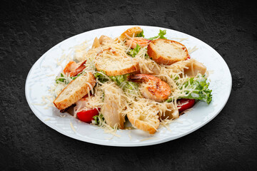 Caesar salad with seafood, egg and fresh vegetables. Isolated on a black background