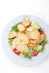 Caesar salad with chicken, egg and fresh vegetables. Isolated on a white background