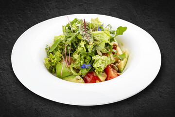 Salad with avocado and pine nuts. Isolated on a black background.