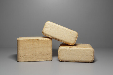 Pressed square wood briquettes on a gray background. Solid fuels from coniferous and deciduous wood shavings