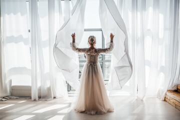 a beautiful bride in a magnificent dress throws the curtains