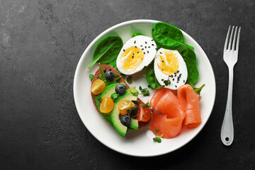 Delicious breakfast, tapas, appetizer. Bread, vegetables, herbs, spinach, eggs, salmon, berries, blueberries. Top view