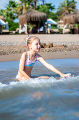 Little girl playing on the beach by the sea