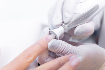 Close up photo of manicurist with Electric Nail Drill in Beauty Manicure Salon