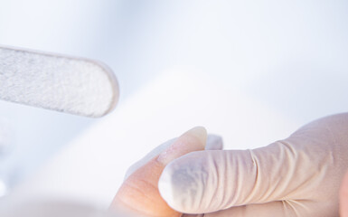 close-up of a gloved manicurist who treats a client's nails with a manicure file